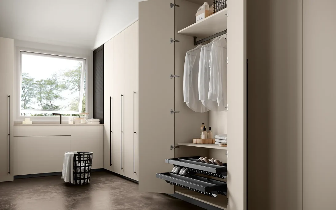 Modern kitchen with beige cabinets, open shelving, and a window overlooking greenery.