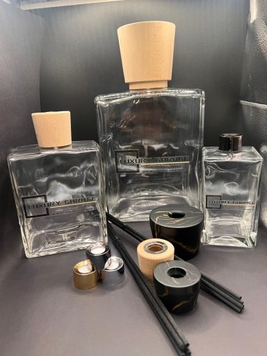 Flaconi di profumo trasparenti e vari oggetti su uno sfondo scuro.