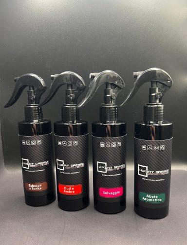 Quattro flaconi spray per capelli, ciascuno con etichetta colorata e pompa nera.