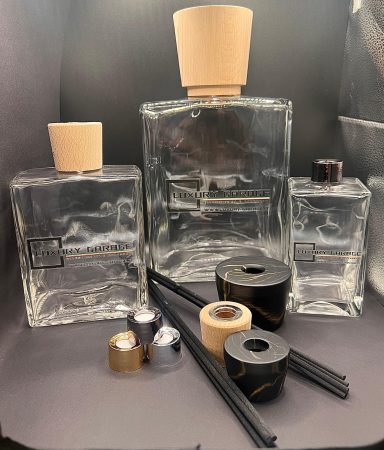 Four glass bottles with wooden caps and decorative tape, alongside black and gold canisters.