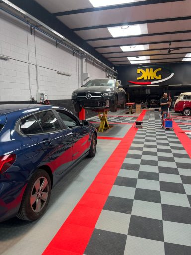 Auto shop interior with a lifted vehicle on a hydraulic lift and a checkered floor.