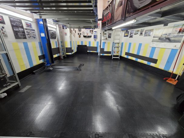 Laboratory or workshop interior with striped walls and black flooring, featuring equipment.